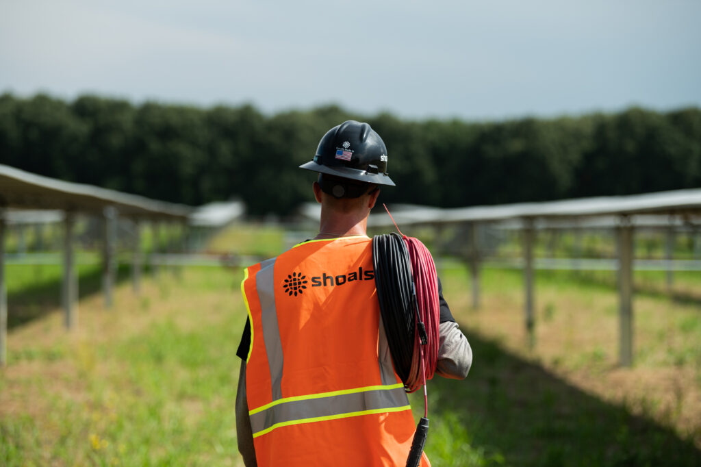 Técnico de Shoals transportando cableado en una planta fotovoltaica